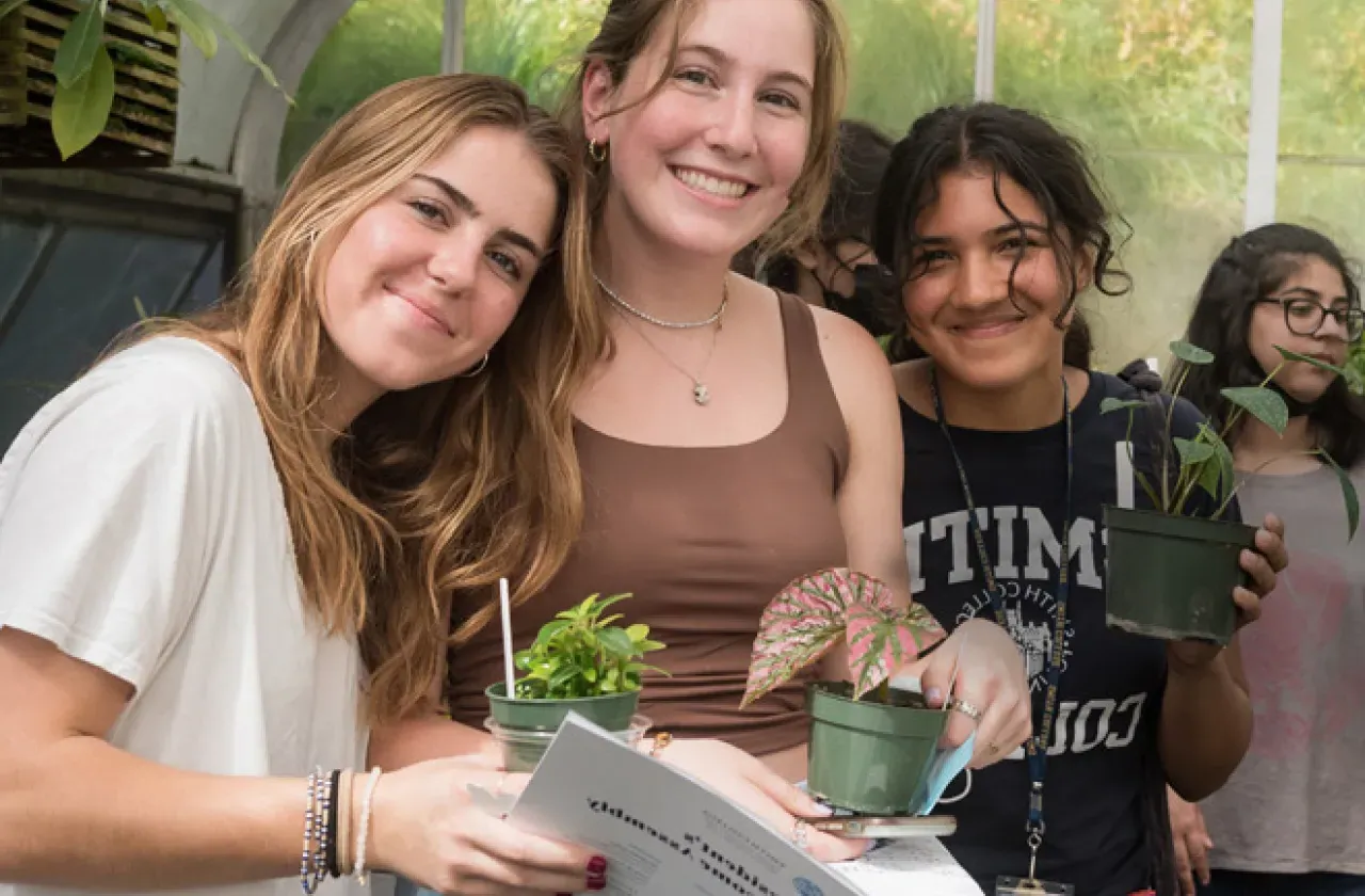 Three new students pick out plants in the greenhouse.